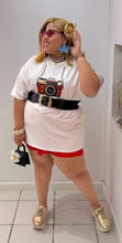 Load image into Gallery viewer, Person wearing a white t-shirt with a camera design, red shorts, and gold shoes in a store setting.
