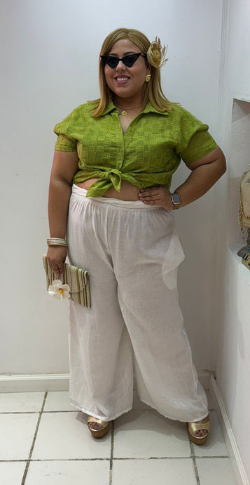 Woman in a green top and white pants posing in a store
